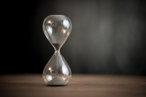 Hourglass on the wooden table background